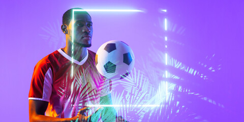 African american male soccer player with ball standing by illuminated square and plants © vectorfusionart