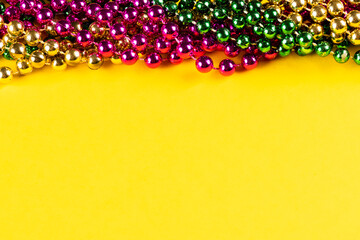 Composition of colourful mardi gras beads on yellow background with copy space