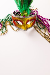 Composition of colourful mardi gras beads and carnival mask on white background with copy space © vectorfusionart