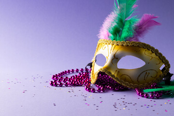 Composition of pink mardi gras beads and carnival mask on blue background with copy space