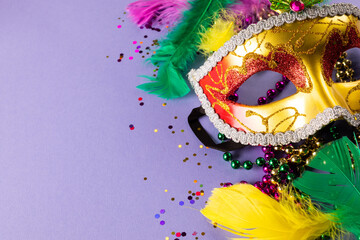 Colourful mardi gras beads, feathers and carnival mask on blue background with copy space