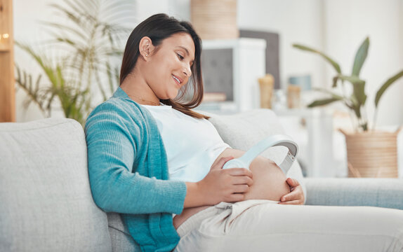 Pregnant, Woman And Stomach With Headphones For Music For Her Unborn Baby While Relaxing At Home. Belly, Baby Bump And Pregnancy With A Mother Using A Headset For Audio Or Podcast Streaming