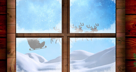 Image of santa claus in sleigh with reindeer seen seen through window