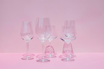 Various empty wine glasses on a pink background with space for text.