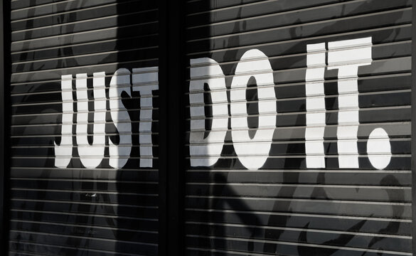 The logo sign of Nike Just do it company on the facade of a store. Clothing apparel industry, Greece 2022.
