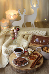 Cup of tea or coffee, various sweets and spices, Christmas decorations, comfy blanket, books and glasses. Selective focus.