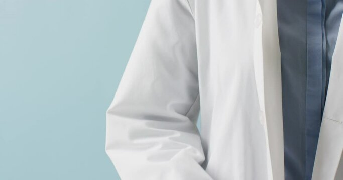 Midsection of caucasian doctor holding stethoscope crossing arms, on blue background with copy space