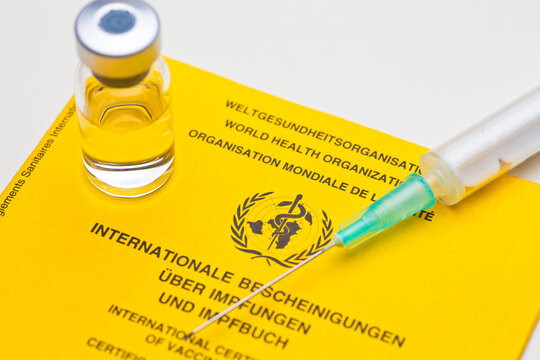 Yellow vaccination document of the world heatlh organization with syringe an vial