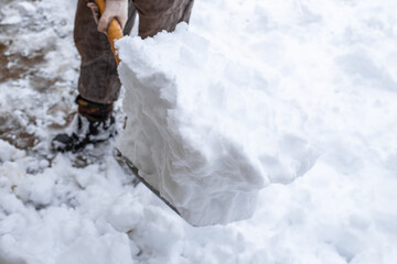 A man removes snow with a shovel on a winter day after a heavy snowfall. selective focus