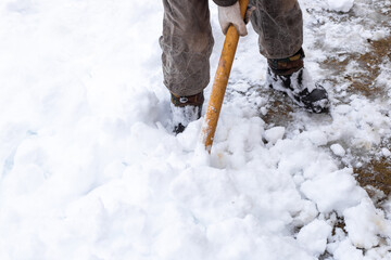 A man removes snow with a shovel on a winter day after a heavy snowfall