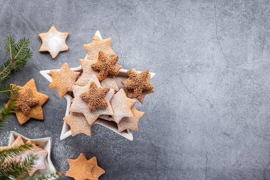 Christmas ginger cookies on a plate in the shape of a star on grey background, flat ley.