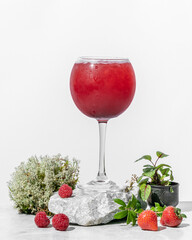 Fresh cold strawberry and raspberry drink with ice with natural herbs and moss as decoration  on white  background closeup
