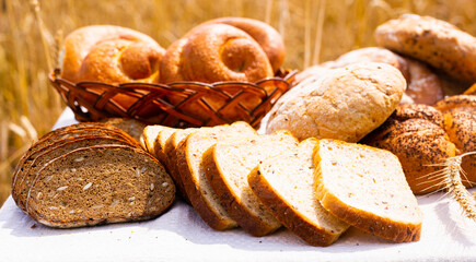 lot of different flavored bread, wheat, rye, on the table in the field outside