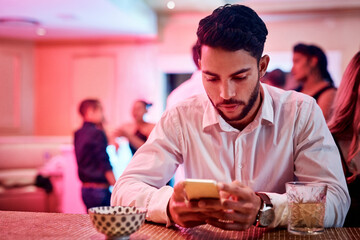 Phone, party and waiting with a man in a nightclub, checking his text message alone while his date...