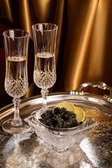 Black caviar with crystal champagne glasses in luxury interior