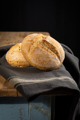 View of two quinoa buns on dark cloth, on rustic wooden table, black background, vertical, with copy space