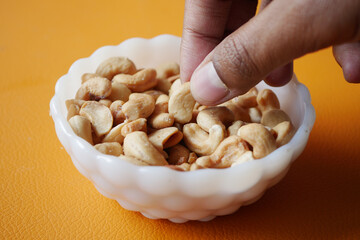 hand pick a cashew nut from a small bowl