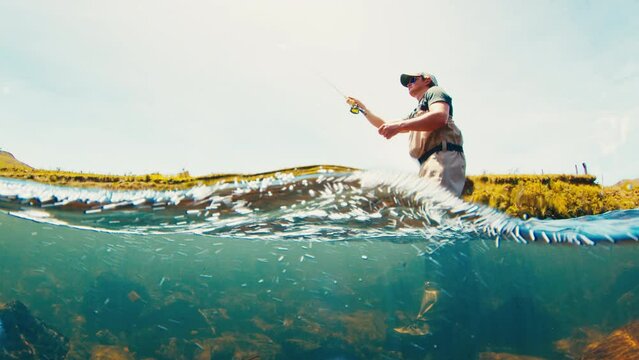 Fly fishing splitted underwater view. Angler casts the fly on the rapid river