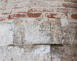 old brick church wall with scratched crosses
