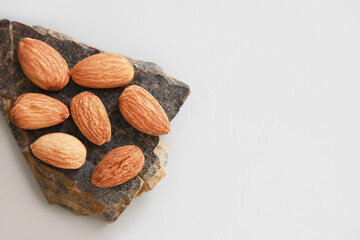 small grains of natural brown almonds on a marble stone on a gray background