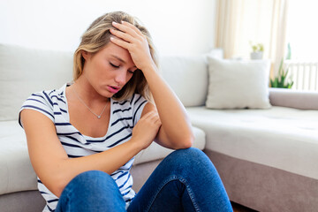 Head shot woman anxious worried woman sitting on couch at home. Frustrated confused female feels unhappy, problems in personal life, quarrel break up with boyfriend and unexpected pregnancy concept.