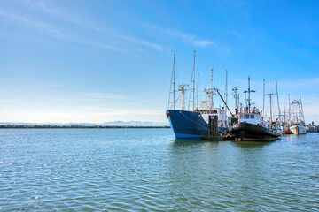Naklejka premium Small fishing trawler and tugboat moored at the ocean pier