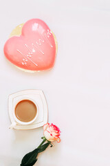 Pink tea rose with heart shaped pink mousse cake with a cup of coffee.