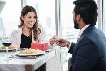 Unexpected moment in man's giving present to businesswoman with city background at restaurant hotel	