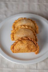 Close up of fried Argentine empanadas on a white plate.
