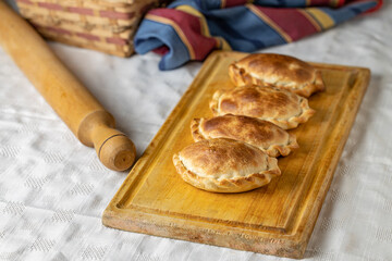 Traditional baked Argentinian empanadas on a board. Copy space.