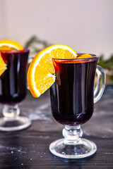 Glass of delicious glintwein or mulled hot wine, cinnamon, thread on vintage wooden background.