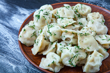 Traditional russian pelmeni or ravioli, dumplings with meat on wood black background. Russian food and russian kitchen concept.
