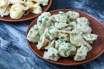 Traditional russian pelmeni or ravioli, dumplings with meat on wood black background. Russian food and russian kitchen concept.