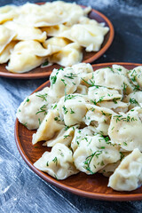 Traditional russian pelmeni or ravioli, dumplings with meat on wood black background. Russian food and russian kitchen concept.