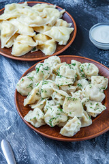 Traditional russian pelmeni or ravioli, dumplings with meat on wood black background. Russian food and russian kitchen concept.