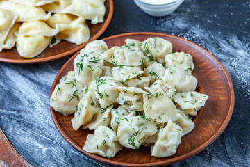 Traditional russian pelmeni or ravioli, dumplings with meat on wood black background. Russian food and russian kitchen concept.