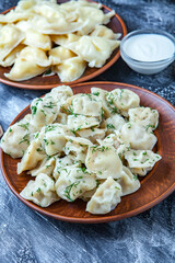 Traditional russian pelmeni or ravioli, dumplings with meat on wood black background. Russian food and russian kitchen concept.