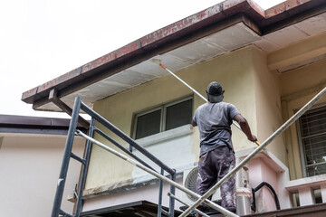 Fototapeta na wymiar Painter worker adding undercoat foundation paint onto ceiling with roller at residential building