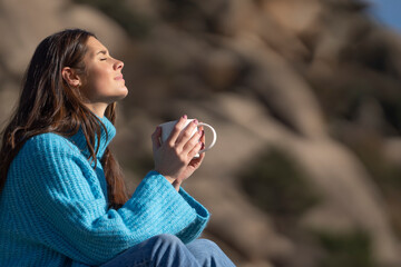 Side view portrait of a relaxed woman enjoying a cup of coffee in the high mountains