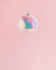 Sparkly disco Christmas bauble ornament on a soft pink background. New Year's countdown moments. Celebration concept idea