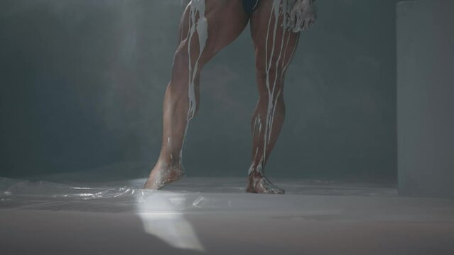 White paint or clay flow over a male muscular leg