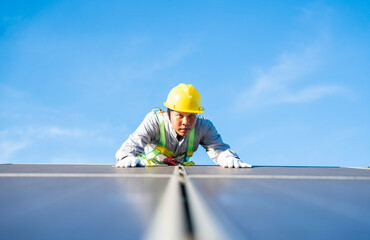 Fototapeta premium MaleAsia technician wearing protective clothing for safety climbs to install solar panel at solar farm using sunlight to produce solar electricity.Renewable Energy and Electricity Concept