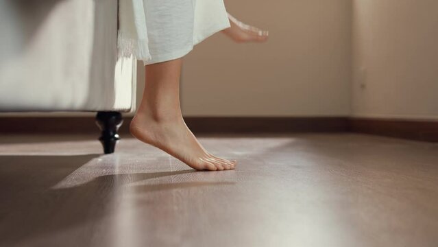 Close-up Asian girl foot step down on bed with white pajamas wake up walk to open curtain on window fresh peaceful morning light empty floor in bedroom at home. Female morning lifestyle concept.