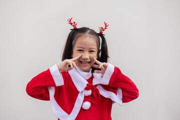 Portrait shot of adorable asian kid girl with red sweater for Christmas costume on white background shows concept of happiness celebration. It is the emotional face expression of enjoyment.