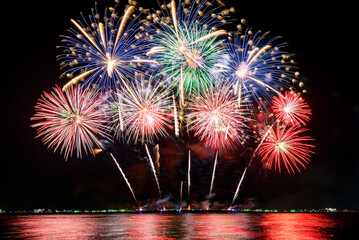 Amazing beautiful colorful fireworks display on celebration night, showing on the sea beach with...
