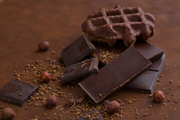 Composition of bars and pieces of different milk and dark chocolate, grated cocoa brown background top view