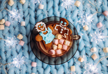 Couple made out of an gingerbread that soak in cup of hot chocolate with marshmallows, cozy winter setting. Winter spa concept.