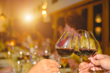 Three female friends clinking three glasses of wine. They happily drank red wine at the feast.