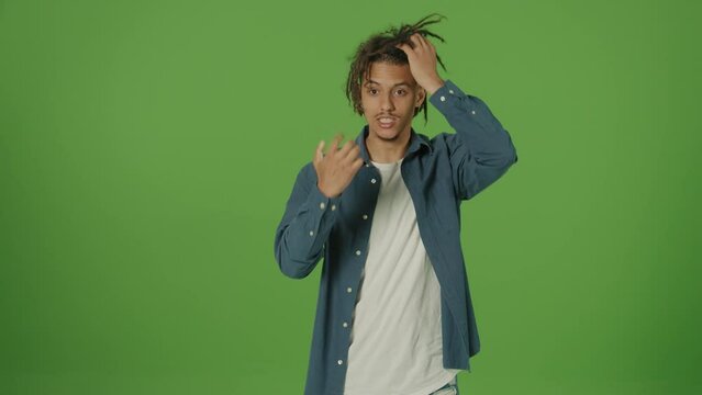 Angry Young Multicultural Curly Freelancer Student Man in Denim Shirt Emotionally Explaining Something to the Camera Waving Hands and Showing Fists on Green Screen Background