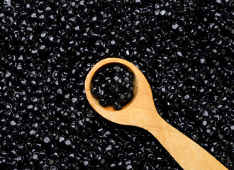 Black caviar with a wooden spoon, background. Top view